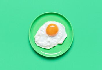 Fried egg on minimalist on a green background, view from above