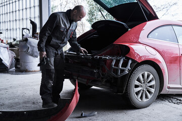 Naklejka premium Car service worker repairs restores car