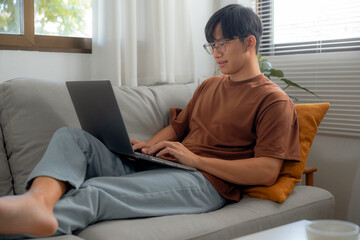Fototapeta premium Work at home young asian man working on laptop computer while sitting at home Morning lifestyle