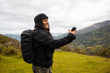 mujer excursionista video llamada con un smartphone en el acantilado de la montaña junto al fondo de nubes ,invierno,
