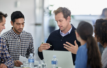 Making sure it makes sense to the staff. Group of colleagues sitting round a meeting table having a serious discussion.