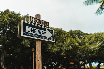 Beautiful shot of One Way Hotel Street Sign In Downtown Hawaii with trees and a light sky