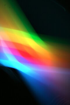 Luces en arcoiris a trav&egrave;s de un prisma con movimiento y desenfoque de luz incidente, refracta un bello dise&ntilde;o abstracto multicolor con fondo negro 