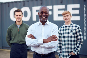 Portrait Of Male Multi-Cultural Freight Haulage Team Standing By Shipping Container