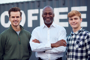 Portrait Of Male Multi-Cultural Freight Haulage Team Standing By Shipping Container