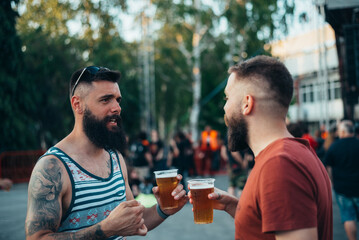Two handsome friends drinking beer and having fun at music festival