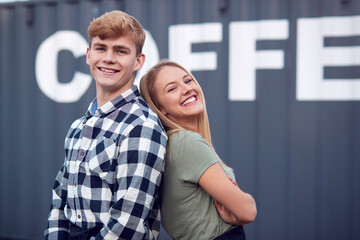 Portrait Of Male And Female Interns At Freight Haulage Business Standing By Shipping Container 