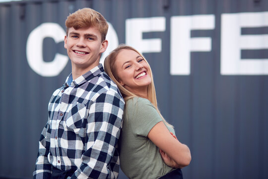 Portrait Of Male And Female Interns At Freight Haulage Business Standing By Shipping Container 