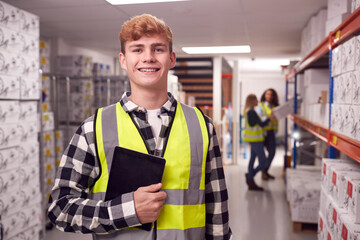 Portrait Of Male Worker Inside Busy Warehouse Checking Stock On Shelves Using Digital Tablet  - obrazy, fototapety, plakaty