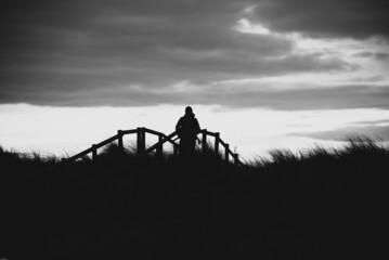 Grayscale shot of a silhouette of a person standing on the background of clouds © Will Griffiths/Wirestock Creators