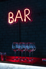 Glasses on bar neon sign background