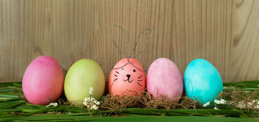 colorful easter eggs and one like rabbit in the center and rustic wooden background 
