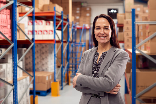 Portrait Of Female Team Leader Standing By Shelves In Warehouse 