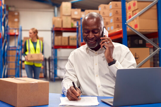 Male Team Leader Working On Laptop Talking On Mobile Phone
