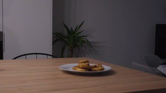 Man walking past a plate of cookies and eating all of them, concept for cravings and hunger