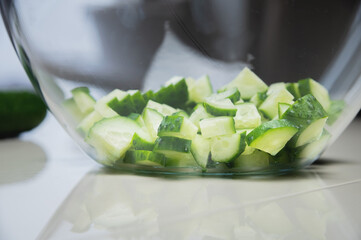 Fresh cucumber sliced for cooking vegetable salad in a glass transparent bowl on the kitchen table....
