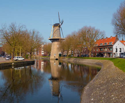 a windmill in schiedam in Holland with a river in front