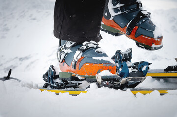 Close-up of freeride ski boots on snow. Skitour concept. Used worn boots on a male skier against the background of a glacier in cloudy weather in the mountains