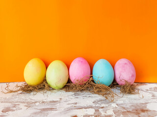 standing and queued colored eggs on orange background representing easter 