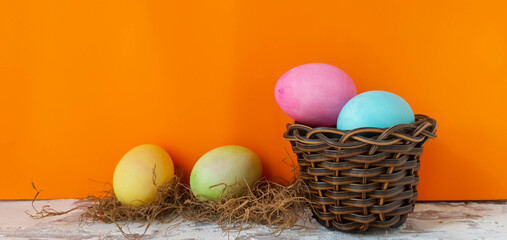 colored eggs in straw nest and background with space to copy orange 