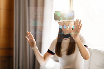 Woman in VR glasses. Confident young woman in virtual reality headset pointing in the air while sitting at her working place in office