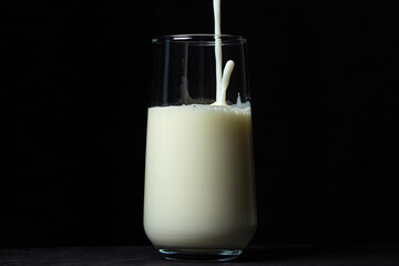 Glass of milk on a black background. Milk is poured into a transparent glass. natural healthy drink