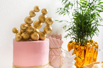 Holiday birthday table with cake and ballons. Pink and golden decoration
