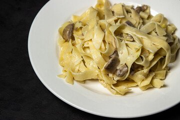 Italian pasta with mushrooms on a black background. Traditional home cooking.