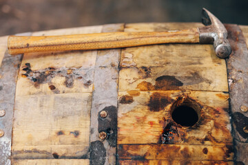 Hammer on dusty whiskey barrel with open bung hole