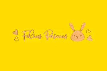 Felices pascuas escrito con letras de madera junto a una cara de conejo y corazones de madera sobre...