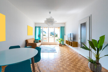Living room with table and chairs in the foreground, sofa and cabinet with television. in the background large bright window