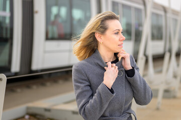 Woman in overcoat walking along a platform at a station