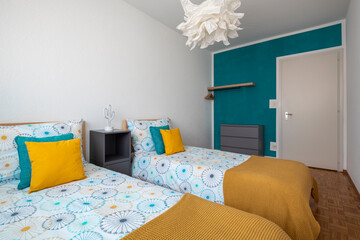Spacious room for children with two single beds, colored sheets and lots of pillows