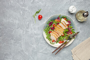 Chicken breast on the leaves arugula with radichio, tomatoes and onions. Balanced lunch. Top view