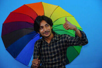 Young handsome man holding colorful umbrella and giving amazed expression, fear and excited face.