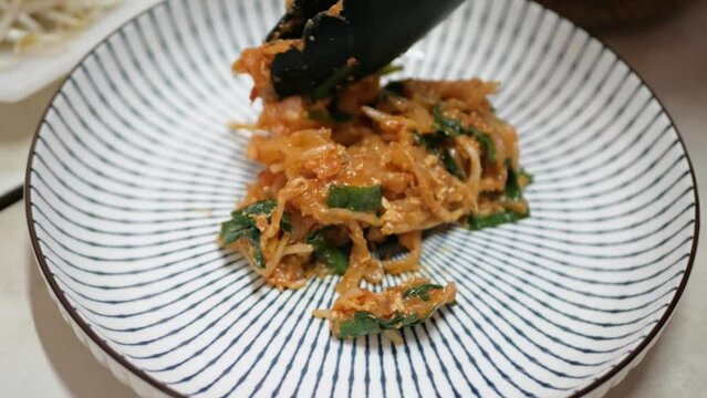 Putting padthai - traditional famous thai street food into the dish with bean sprouts for lunch-dinner