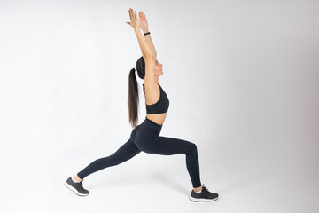 Fototapeta na wymiar Portrait of mature girl stretching her arms on white background. Attractive brunette woman in fashionable sportswear exercising. Healthy lifestyle, sport concept