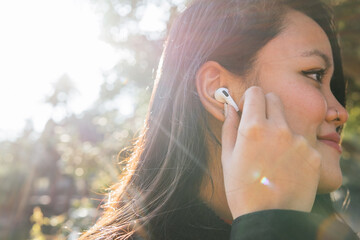 Ethnic woman putting wireless earbuds in ear