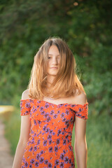 Portrait of a young beautiful girl with disheveled hair in a summer park.