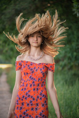 Portrait of a young beautiful girl with disheveled hair in a summer park.