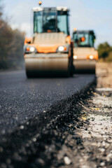 Blurred background of vibratory asphalt rollers compactor compacting new asphalt pavement. Road service building new highway