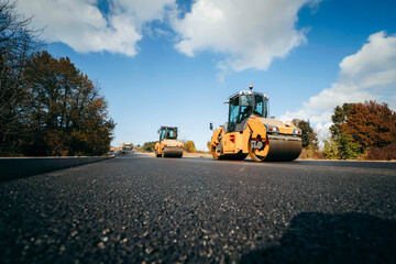 Vibratory asphalt rollers compactor compacting new asphalt pavement. Road service build a new highway