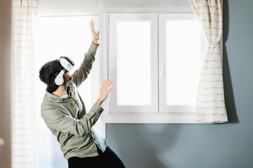 Young man exploring cyberspace in VR goggles at home