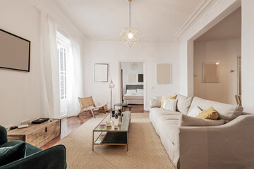 Living room with light fabric sofa, wooden doors with stained glass windows, balconies with gauzy white curtains and large beige rug on the floor