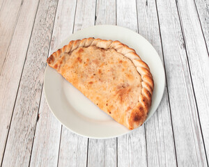 calzone is a specialty of Italian cuisine made in a similar way to pizza but completely closed by a dough; it can be stuffed with cheese, meat, vegetables, or other condiments, and is baked or fried