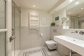 Bathroom with one-piece sink, square-framed mirror, decorative objects, radiator to dry towels,...