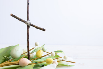Christian cross and white tulips and easter eggs on a white background with copy space
