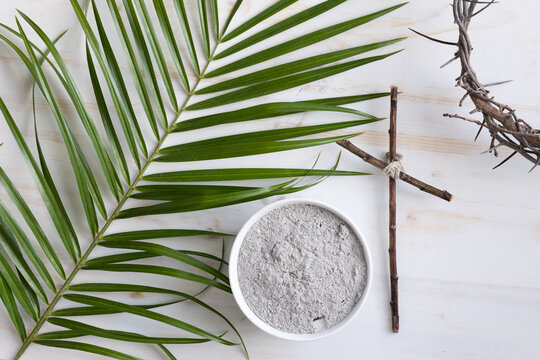 crown of thorns, palm branch, bowl of ashes and small christian cross on white background