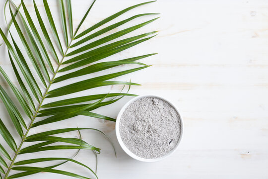 bowl of ashes and palm branch on white wood background