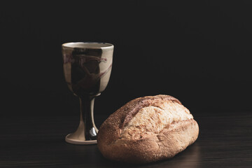 Clay chalice with a loaf of artisan bread on a black background